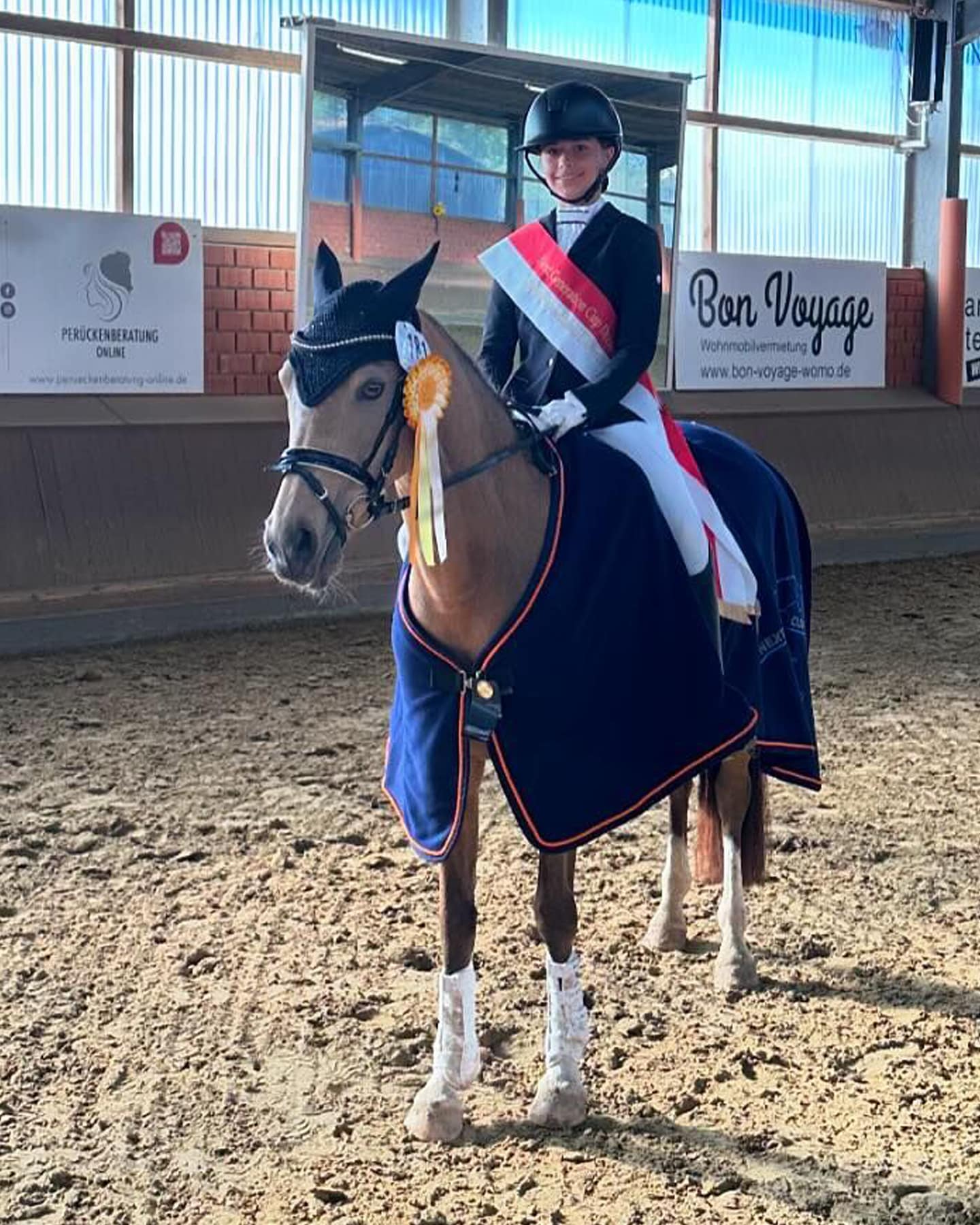 Sieger Next Generation Cup Dressur Junge Reiterin mit Siegerschärpe reitet auf Pferd in Reithalle